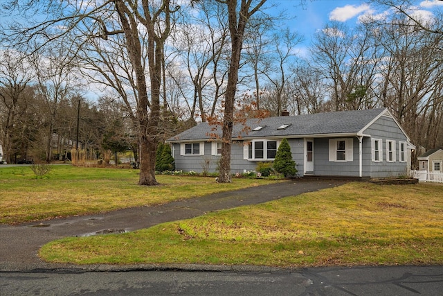 ranch-style home featuring roof with shingles, a front lawn, driveway, and a chimney