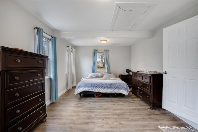 bedroom with light wood-style floors, baseboards, and attic access