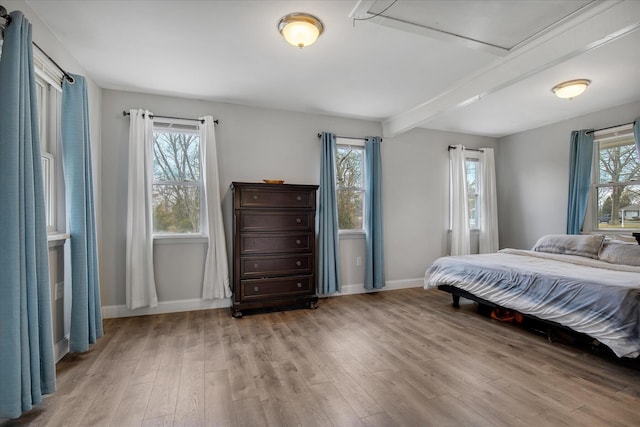 bedroom with baseboards, beam ceiling, and wood finished floors