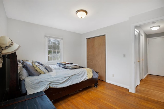 bedroom with wood finished floors, baseboards, and a closet