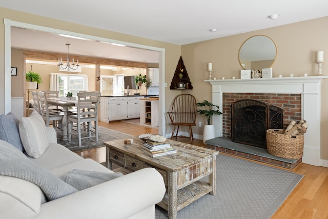 living room featuring a fireplace, light hardwood / wood-style floors, and a chandelier