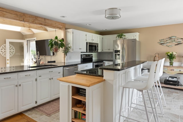 kitchen featuring white cabinets, a kitchen island, sink, backsplash, and stainless steel appliances