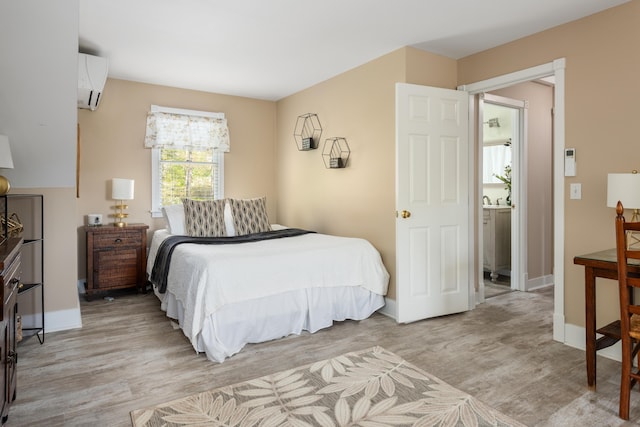 bedroom with an AC wall unit and light hardwood / wood-style floors