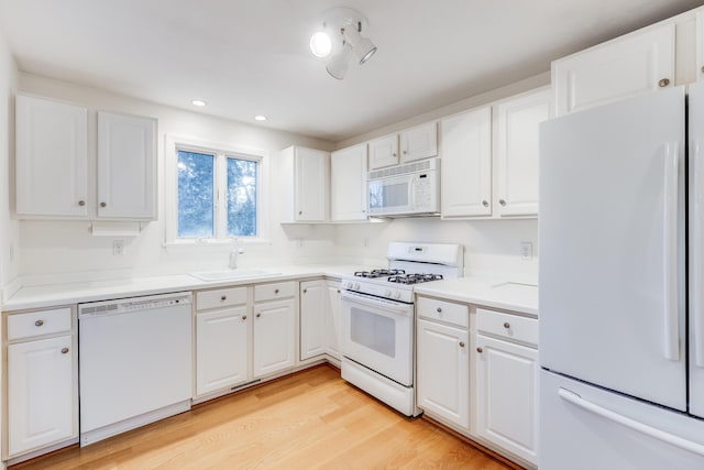 kitchen featuring a sink, white appliances, light wood-style floors, and white cabinets