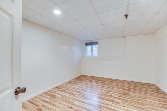 below grade area featuring a drop ceiling, baseboards, and wood finished floors