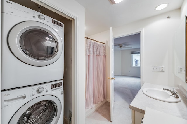 washroom with laundry area, light tile patterned floors, stacked washer / drying machine, and a sink