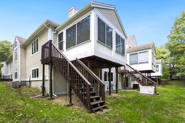 back of property featuring a sunroom, a lawn, and central air condition unit