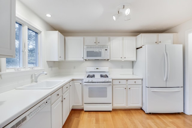 kitchen featuring white appliances, a sink, light countertops, white cabinets, and light wood-type flooring