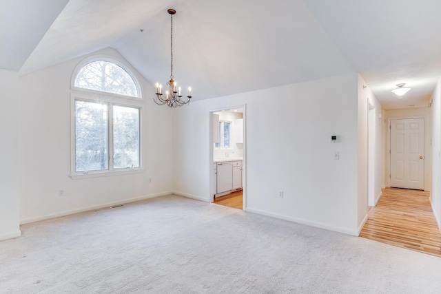 spare room featuring baseboards, visible vents, an inviting chandelier, lofted ceiling, and light colored carpet