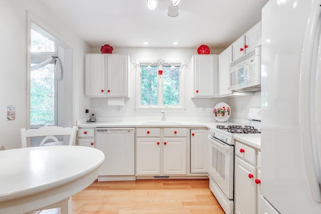 kitchen with sink, white cabinetry, white appliances, and light hardwood / wood-style floors