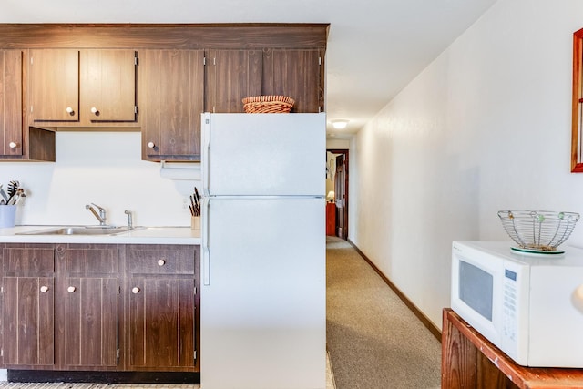 kitchen featuring white appliances, sink, and light carpet