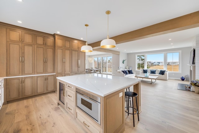 179 Beebe Acres Rd, Falmouth, MA 02540 - kitchen featuring a center island, stainless steel microwave, open floor plan, light wood-style floors, and a breakfast bar