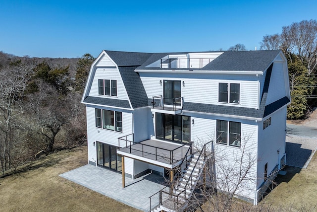 179 Beebe Acres Rd, Falmouth, MA 02540 - back of house featuring a gambrel roof, a patio area, a balcony, a lawn, and a shingled roof