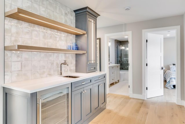 179 Beebe Acres Rd, Falmouth, MA 02540 - bar with beverage cooler, light wood finished floors, a sink, tasteful backsplash, and indoor wet bar