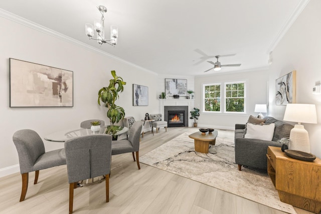 living room featuring light wood-type flooring, ceiling fan with notable chandelier, and ornamental molding