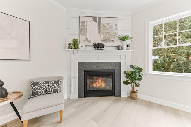 living area featuring a tile fireplace, light wood-type flooring, and ornamental molding