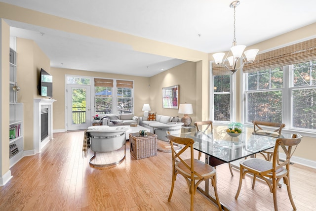 dining space featuring baseboards, a healthy amount of sunlight, a chandelier, and light wood-type flooring