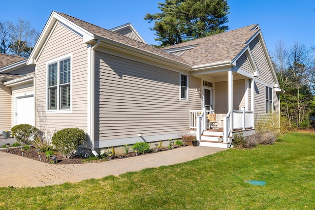 view of side of home featuring a lawn, a shingled roof, and a garage