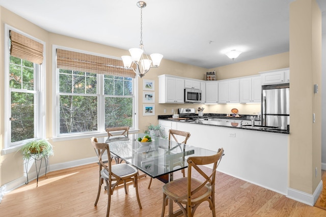 dining room featuring a chandelier, light wood-style floors, and baseboards
