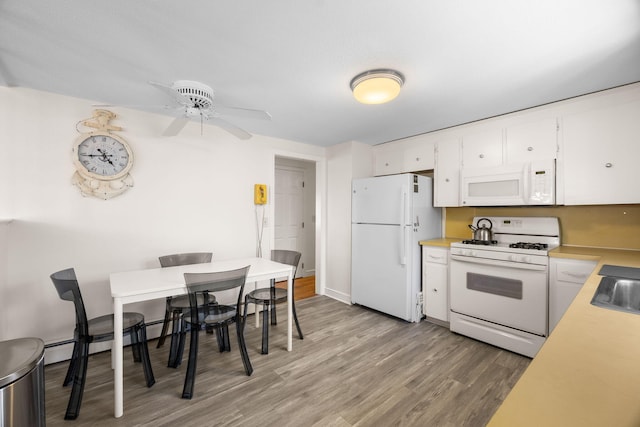 kitchen with light countertops, light wood-style flooring, a baseboard heating unit, white cabinetry, and white appliances