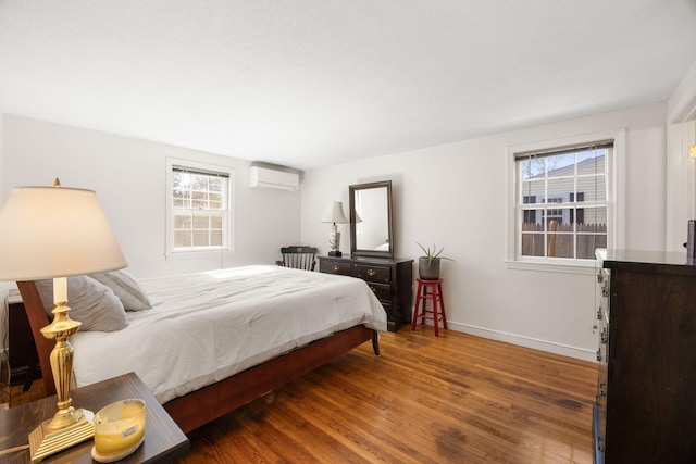 bedroom featuring dark wood-style flooring, an AC wall unit, and baseboards