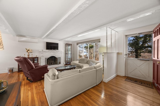 living area with light wood-type flooring, a fireplace, baseboards, and an AC wall unit