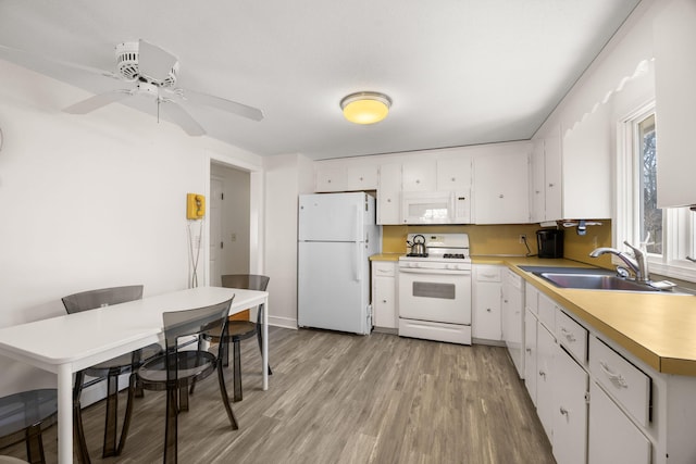 kitchen featuring white appliances, light countertops, light wood-style floors, white cabinetry, and a sink