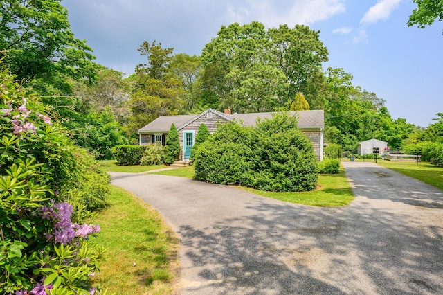 view of front of home featuring aphalt driveway, a front yard, and roof with shingles