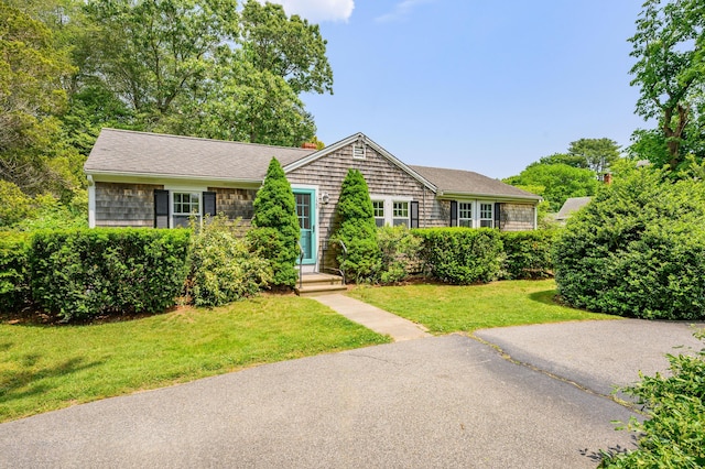 view of front of property with a shingled roof and a front lawn