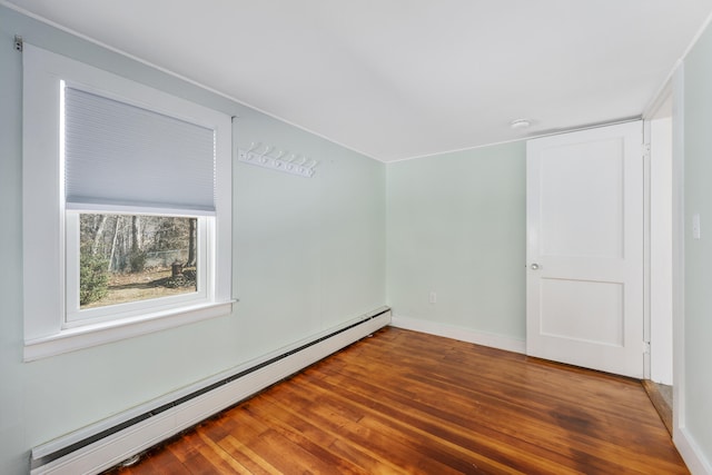 empty room with a baseboard radiator, baseboards, and wood finished floors