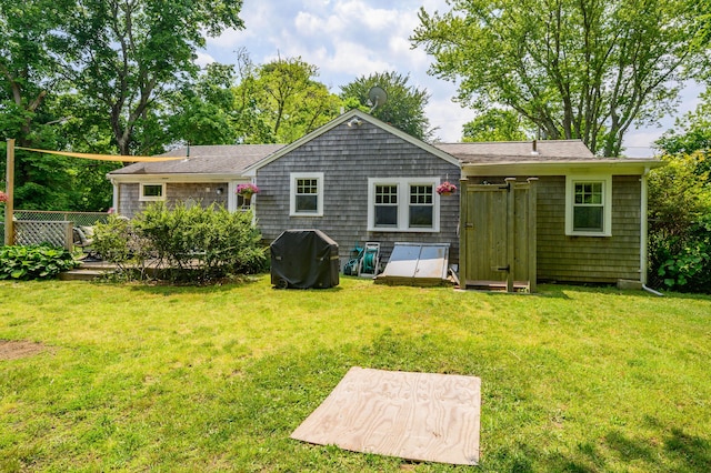 back of property with a lawn and fence