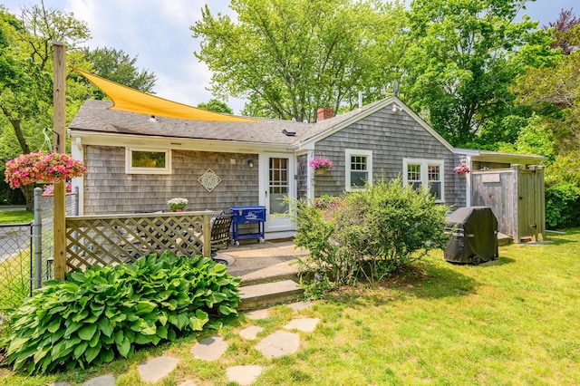 rear view of house with a chimney, fence, and a yard