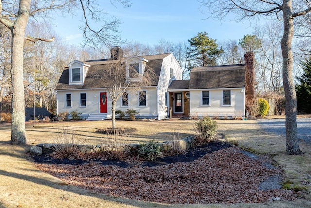 dutch colonial featuring a shingled roof, entry steps, a chimney, and a gambrel roof