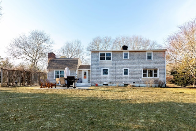 rear view of property with a patio, a chimney, and a lawn