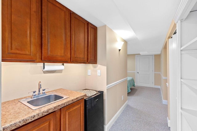 kitchen with brown cabinetry, light countertops, a sink, and light colored carpet