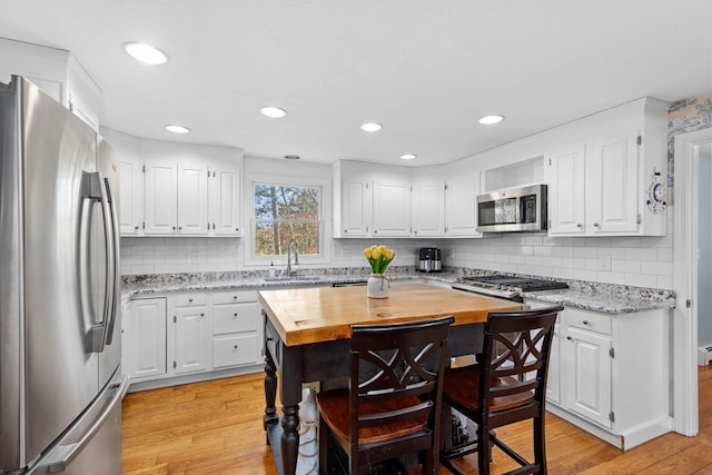 kitchen featuring light wood-type flooring, wood counters, appliances with stainless steel finishes, and a sink