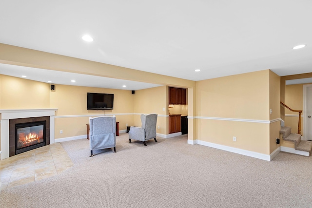 living area featuring a tile fireplace, recessed lighting, light carpet, baseboards, and stairs