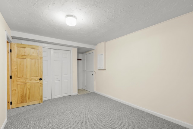 unfurnished bedroom with carpet floors, a textured ceiling, baseboards, and a closet