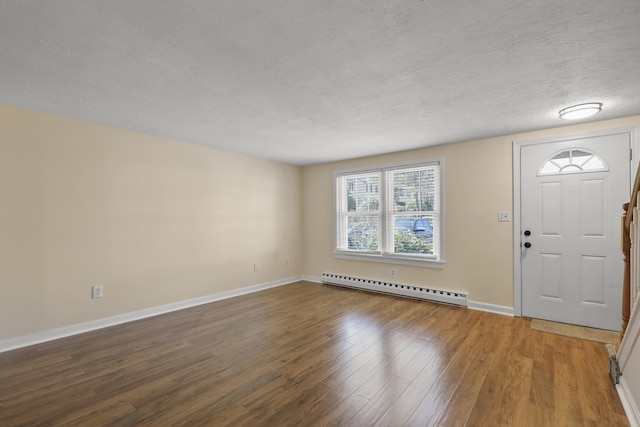 foyer entrance with a textured ceiling, baseboards, a baseboard heating unit, and wood finished floors