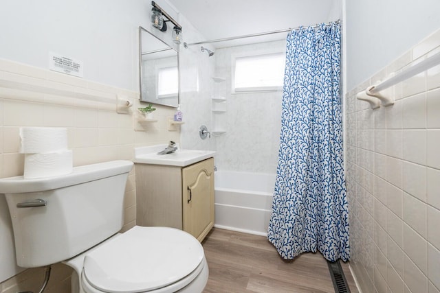 full bathroom featuring wood-type flooring, shower / tub combo, tile walls, toilet, and vanity