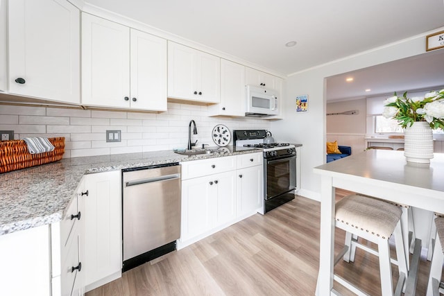 kitchen featuring sink, white cabinets, gas range oven, and dishwasher