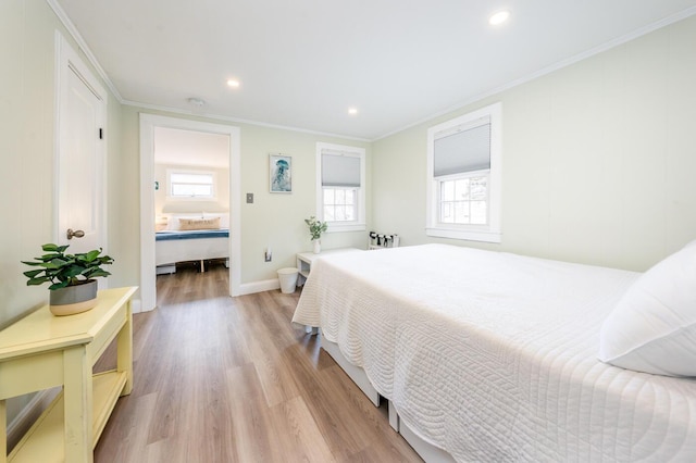 bedroom featuring multiple windows, crown molding, and light wood-type flooring