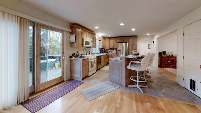 kitchen featuring a kitchen island, stainless steel appliances, a kitchen breakfast bar, sink, and light hardwood / wood-style flooring