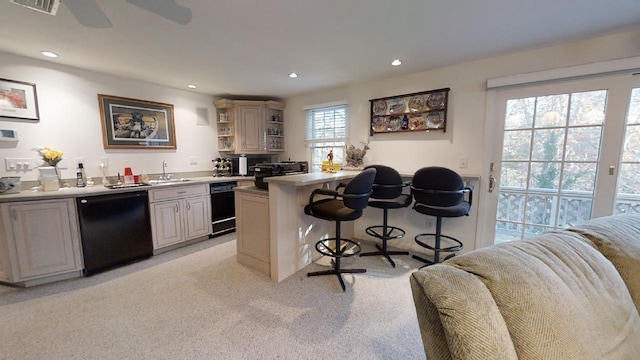 kitchen with sink, light colored carpet, black dishwasher, and a breakfast bar