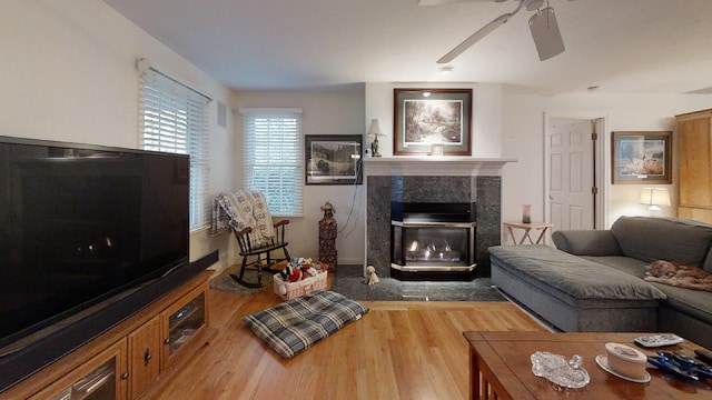 living room featuring a premium fireplace, ceiling fan, and hardwood / wood-style floors