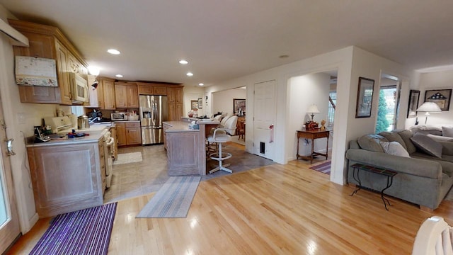 kitchen featuring a kitchen island, light wood-type flooring, a kitchen bar, and stainless steel fridge