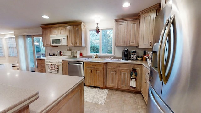 kitchen featuring sink, light tile patterned floors, appliances with stainless steel finishes, and pendant lighting