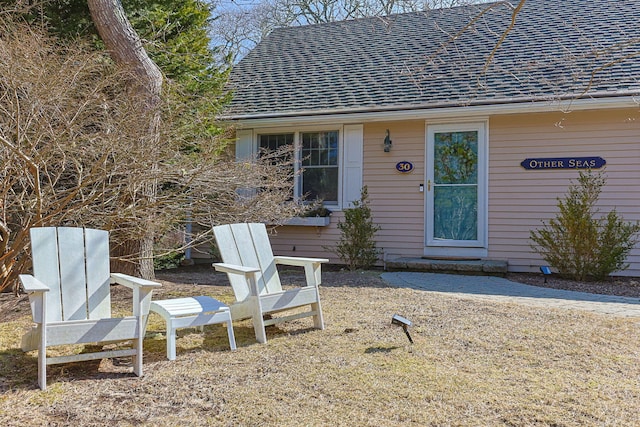 view of exterior entry featuring roof with shingles