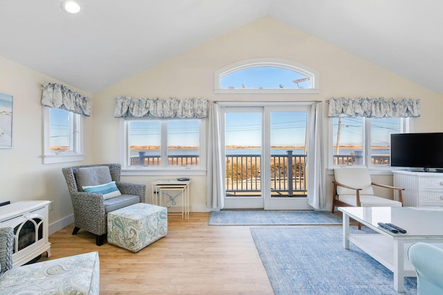 living area featuring vaulted ceiling, light hardwood / wood-style flooring, and a wealth of natural light