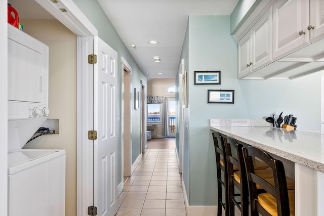 hallway featuring stacked washer / drying machine and light tile patterned floors